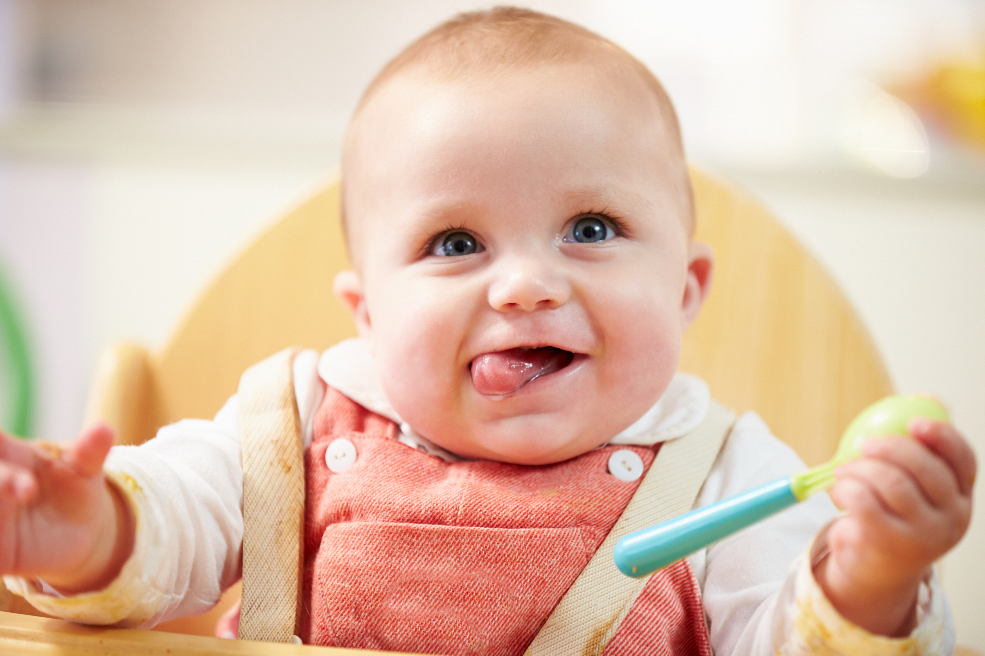 Infant in high chair licking lip ready to eat solids